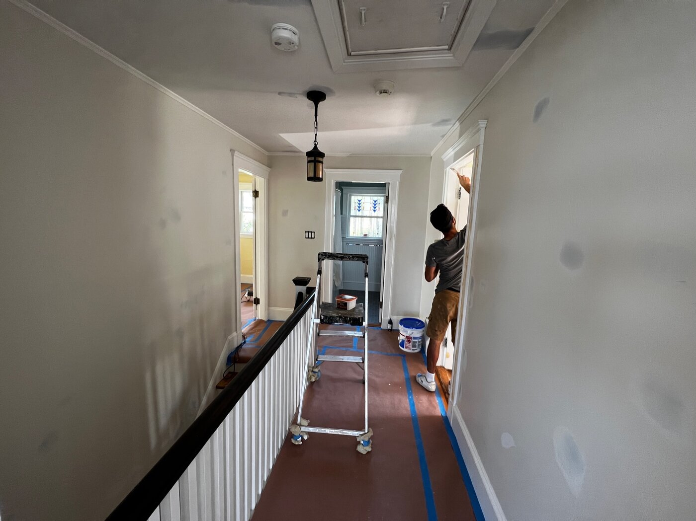 Painter working on a hallway doorway trim
