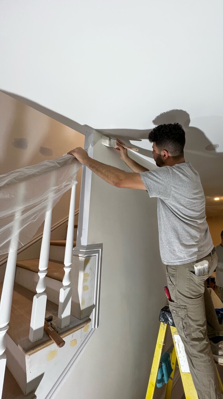 Painter carefully cutting in trim on a staircase